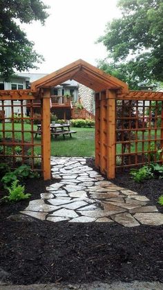 a stone path leading to a wooden arbor