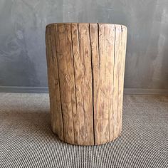 a round wooden table sitting on top of a carpeted floor next to a wall