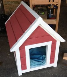 a red and white dog house sitting on the ground