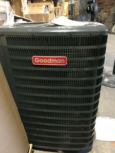 an air conditioner with the word goodman on it sitting next to some boxes