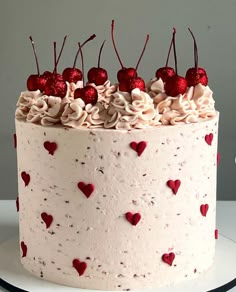 a white cake with red hearts and cherries on it