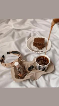 a person pouring caramel sauce into a cup on top of a tray with desserts