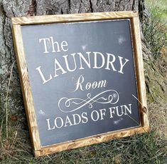 a sign that says the laundry room loads of fun on it next to a tree