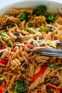 a bowl filled with noodles, broccoli and peppers