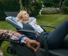 a woman laying on top of a lawn chair next to another person in the grass