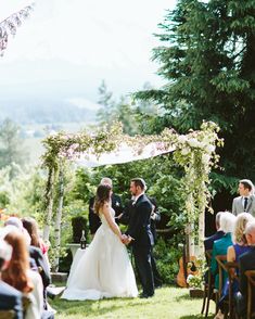 a bride and groom standing at the end of their wedding ceremony under an arch with greenery