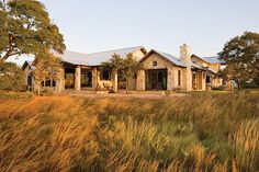 a large house sitting on top of a lush green field next to tall dry grass