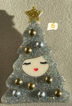 a glass christmas tree with gold and silver balls on it's head, next to a star