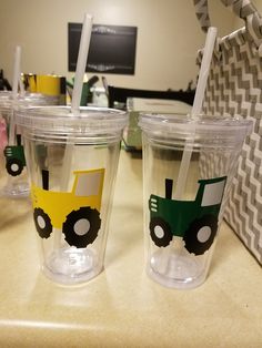 three plastic cups with straws painted on them sitting on a counter in an office