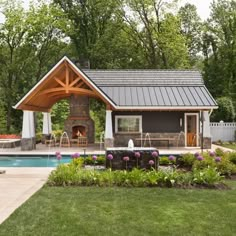 a backyard with a swimming pool and covered patio area next to a large stone fire place