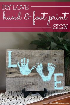 a wooden sign with hand and foot prints painted on it's sides, next to a potted plant