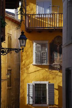 a yellow building with white shutters and a lamp on the side walk next to it