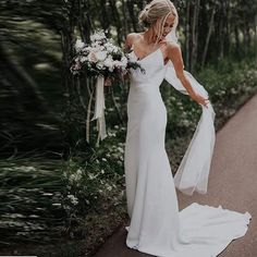 a woman in a white dress is walking down the street with her wedding gown on