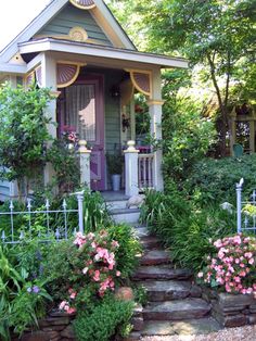 a small house with steps leading up to the front door and flowers on the side