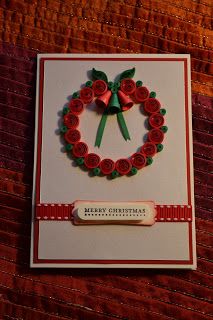 a christmas card with a wreath made out of red paper and green ribbon on it