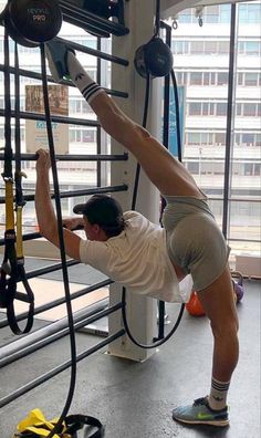 a man is doing exercises in front of the gym equipment that are hanging from the ceiling