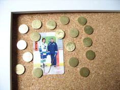 a cork board with some gold coins and a polaroid frame on it, along with two hockey players