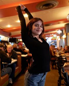 a woman standing in a restaurant raising her arms