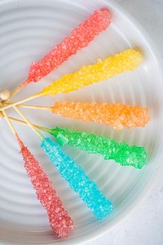 there are five different colored lollipops on a white plate