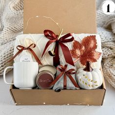 an open box with candles, coffee mugs and other items