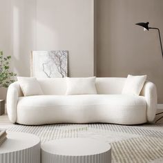 a white couch sitting on top of a rug next to a table and floor lamp