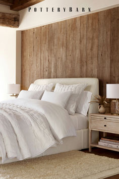 a white bed sitting in a bedroom next to a wooden wall