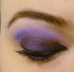 a close up shot of a woman's eye with purple eyeshadow on