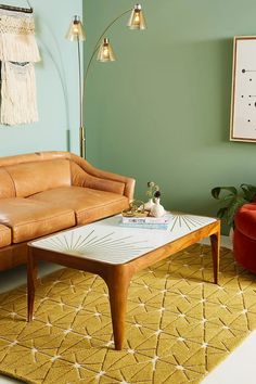 a living room with green walls and a brown leather couch in the corner, next to a coffee table