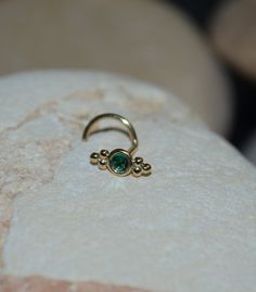 a gold ring with a green stone in the middle sitting on top of a rock