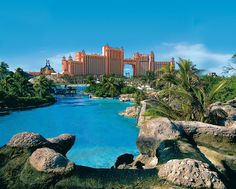 the resort is surrounded by large rocks and palm trees, with blue water in front