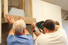 two men working on cabinets in a kitchen