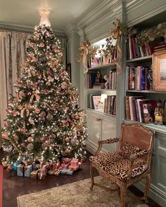 a decorated christmas tree in the corner of a living room with a leopard print chair