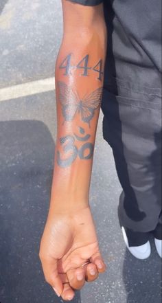 a person with a butterfly tattoo on their arm holding onto another persons hand while standing in a parking lot