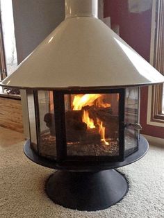 a fire burning inside of a fireplace in a living room next to a rug and window