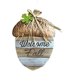 a wooden sign that says welcome fall hanging from the side of a building with an acorn on it