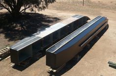 two large metal containers sitting on top of a dirt field