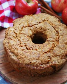 an apple cider cake sitting on top of a wooden cutting board next to apples