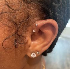 a close up of a person's ear with some piercings on it and hair in the background