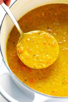 a ladle full of soup being stirred with a wooden spoon