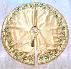 a gold cloth with green beads and tassels on the edge is sitting on a white tile floor