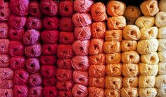 many balls of yarn are stacked on top of each other in different colors and sizes