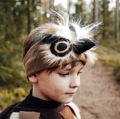 a young boy wearing a brown and white hat with feathers on it's head