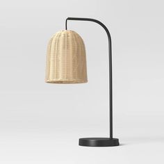 a lamp that is sitting on top of a table with a black base and a rattan shade