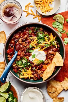 a bowl filled with chili, cheese and tortilla chips on top of a table