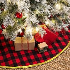 a christmas tree with presents under it on a red and black checkered tablecloth