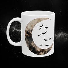 a coffee mug with bats flying over the moon