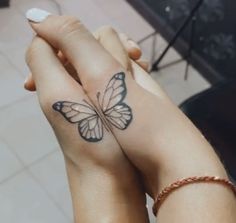 two people holding hands with butterfly tattoos on their wrist and hand, both showing the same tattoo design