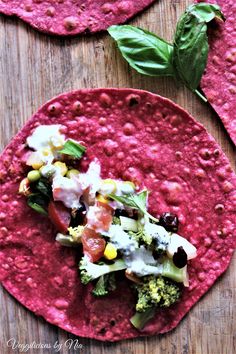 two tortillas with vegetables, cheese and sauce are on a wooden table top