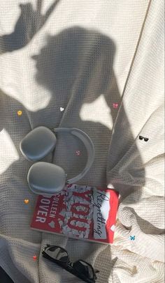 the shadow of a person standing next to a pair of glasses and a book on a bed