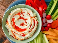 a bowl filled with hummus, celery, carrots and radishes